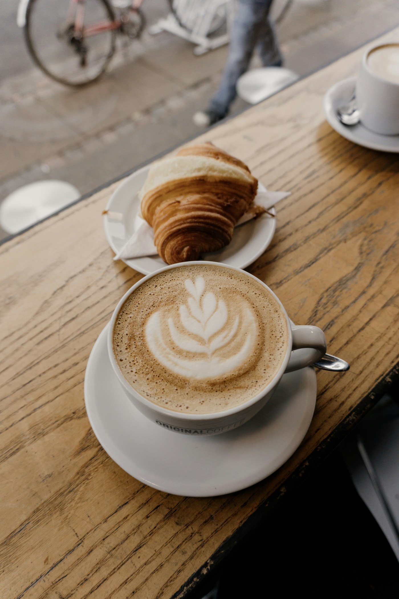 Fresh coffee and a golden croissant in warm morning light